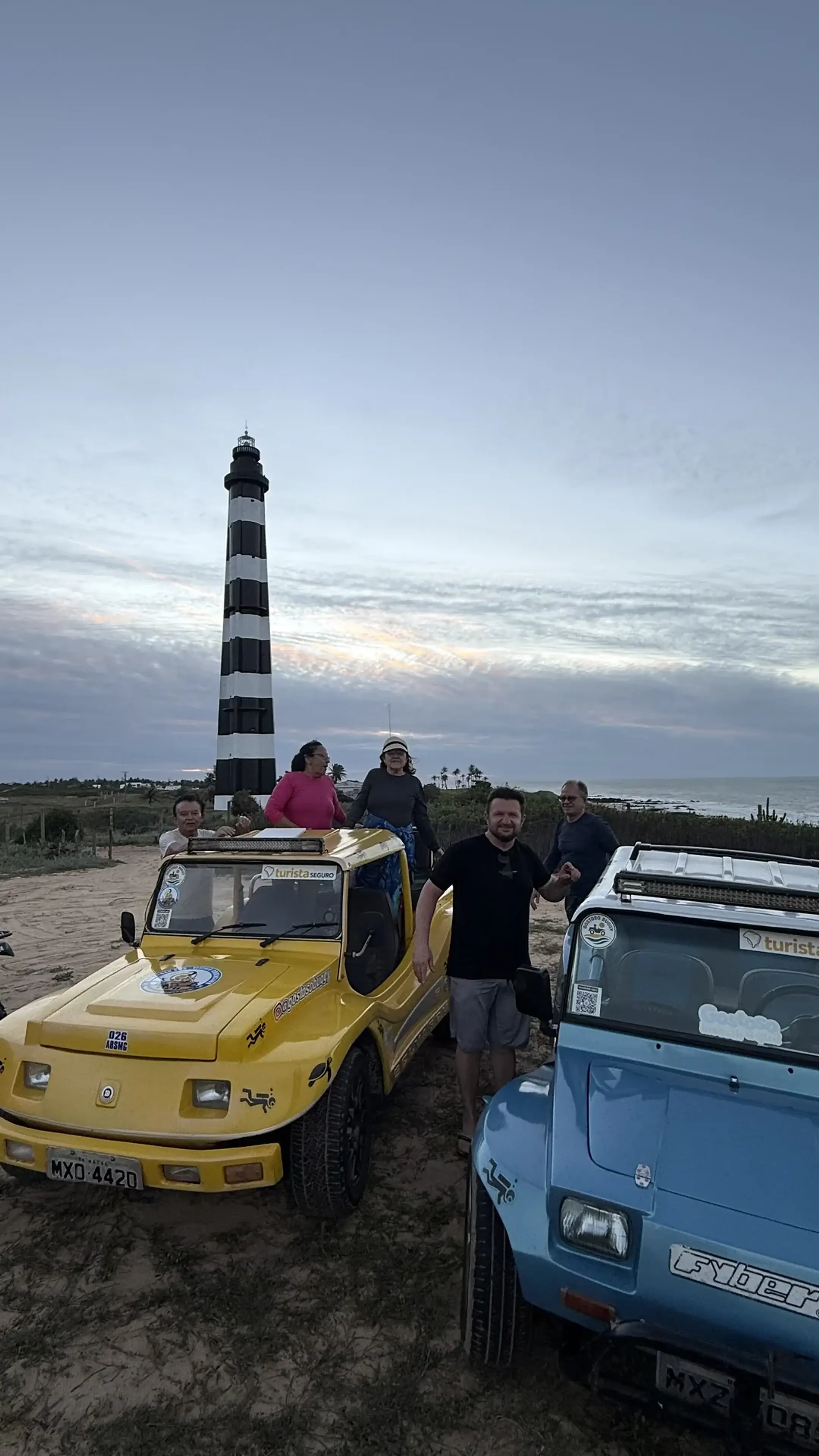 Visitantes e buggies diante de um farol do litoral potiguar