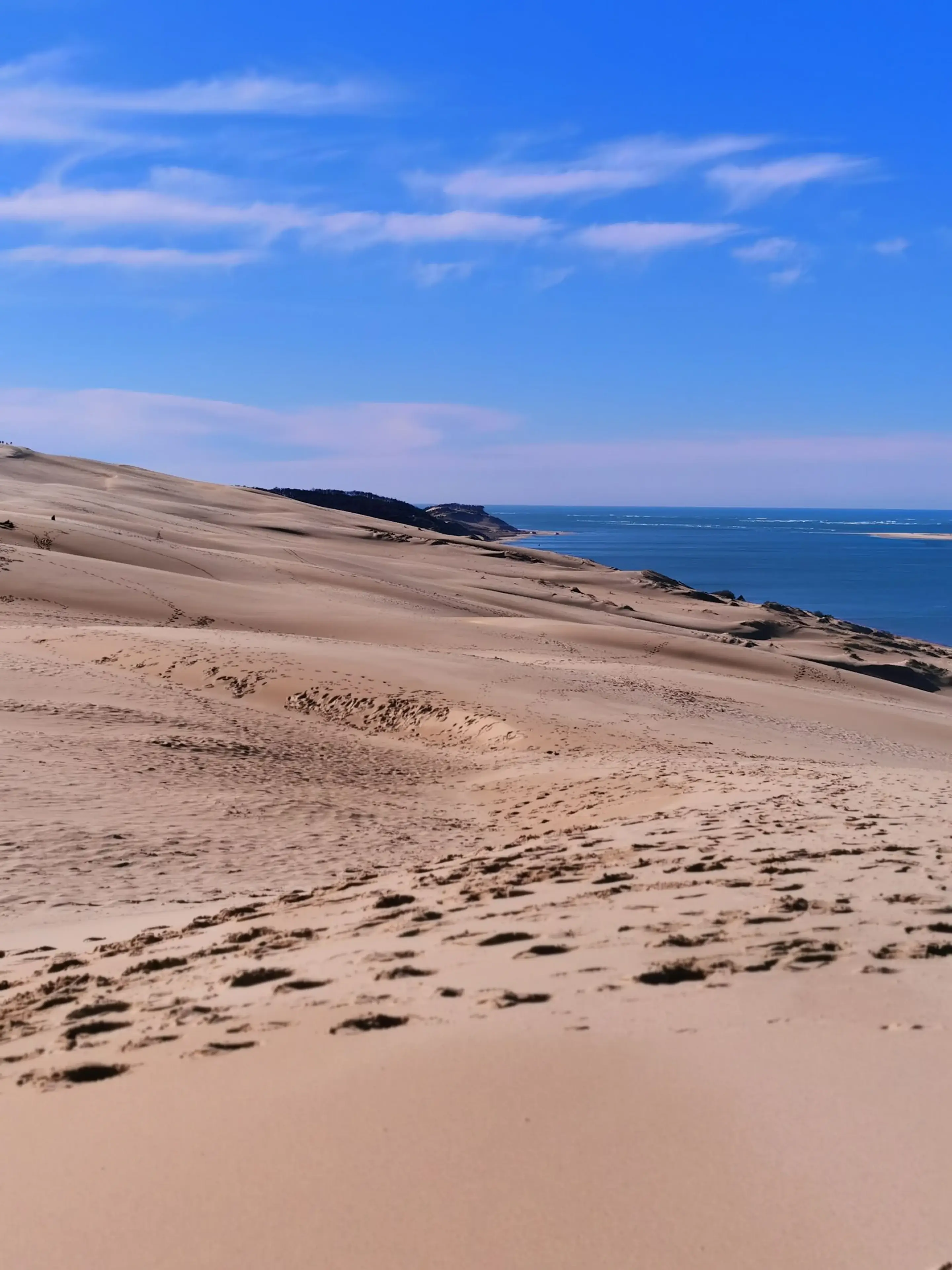 Grande duna encontrando uma faixa de mar azul
